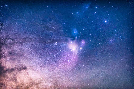 Silhouette of a man, telescope, stars, planets and shooting star under the night sky.