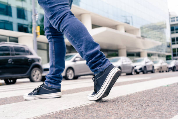 얼룩말이나 보행자 길의 거리를 가로지르는 검은 색 운동화를 입은 남자의 발을 클로즈업합니다. 바이알 교육 - 보행자 뉴스 사진 이미지