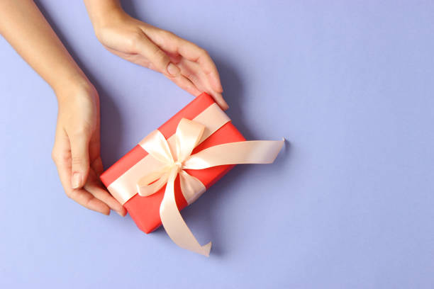 istock gift in female hands on a colored background top view. 1314439891
