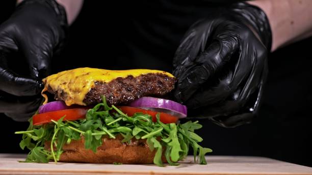 istock Craft burger is cooking on black background. Consist: sauce, arugula, tomato, onion, bacon, currant sauce, ricotta cheese, air bun and marble meat. 1314442385