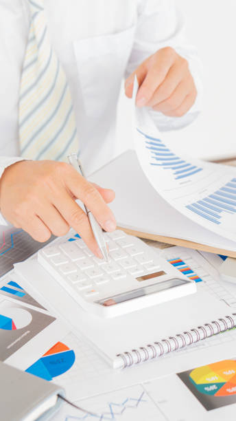 計算機を使用して計算ノートを書き、財務会計の概念に関するグラフ分析を使用してビジネス担当者をクローズアップします。 - tax graph financial report finance ストックフォトと画像