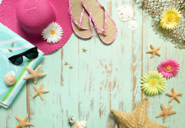 Beach Hat, Flip Flops, Towel and Seashells on an Old Rustic Blue Wood Background