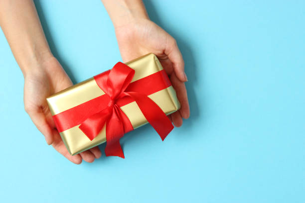 istock gift in female hands on a colored background top view. 1314448675