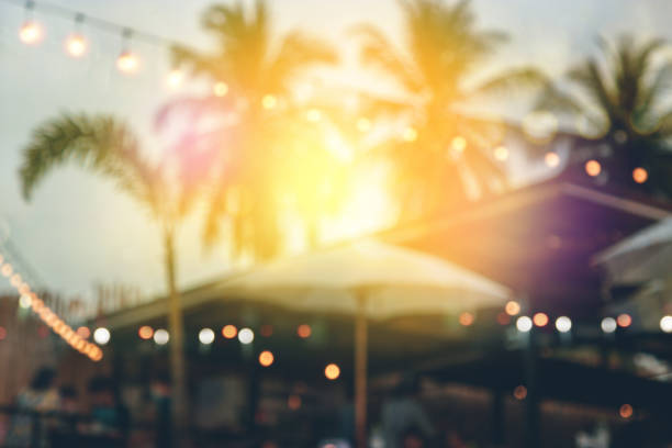 blurred bokeh light on sunset with yellow string lights decor in beach restaurant blurred bokeh light on sunset with yellow string lights decor in beach restaurant beach party stock pictures, royalty-free photos & images