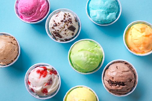 Ice Cream Assortment. Various ice creams or italian gelato on blue background, close up. Frozen yogurt  in small cups - healthy summer dessert.