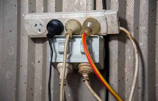 High angle view charging cable in the electrical outlet socket on the wood floor, electrical equipment