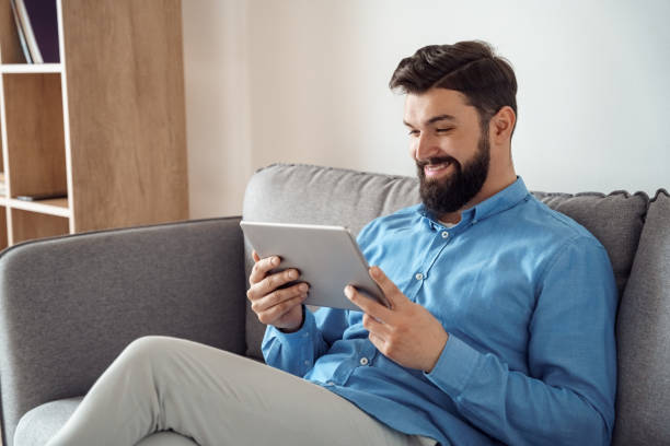 istock Smiling millennial caucasian man watching funny video using mobile tablet 1314452318
