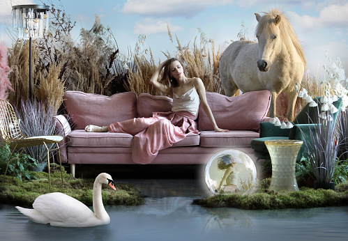 Beautiful fantasy girl in her dreams in an oasis among the water surrounded by greenery with a horse and a swan