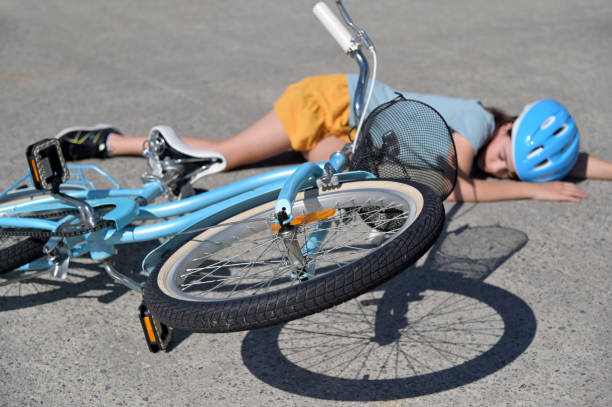 young girl fallen of a bicycle laying down - child bicycle cycling danger imagens e fotografias de stock