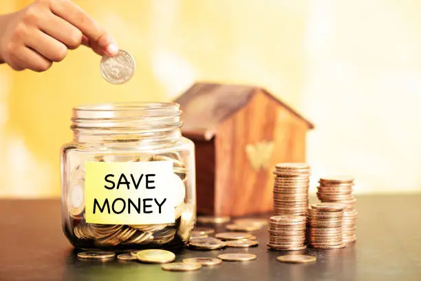 women dropping coins in a bottle to save money for house