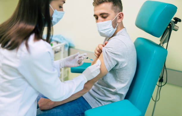 istock Covid-19 or coronavirus vaccine doctor holding syringe and using cotton before making injection to the patient in the medical mask. 1314462167