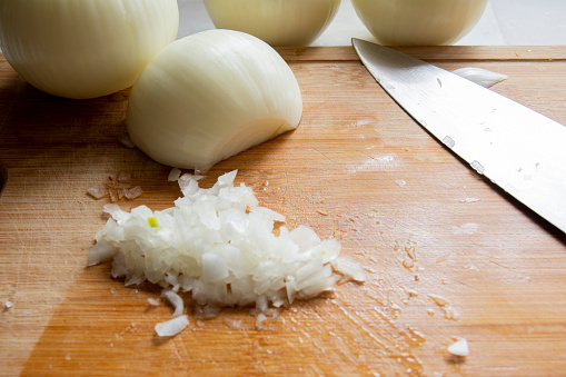 While preparing to make hamburgers, white onions are chopped with a chef's knife. Selective Focus onions. front view