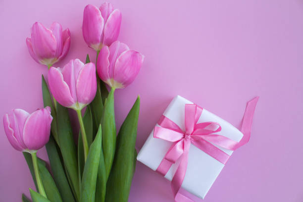 istock Gift box with pink bow and pink tulips on the pink background.Top view.Copy space. 1314463584