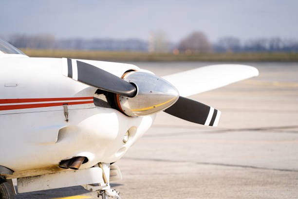 istock Close up front side of white modern jet plane. Clear background with wide road and trees. 1314464978