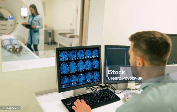 Back View Photo Of A Male Doctor Sitting Near The Computer And Looking On Patient In Magnetic Resonance Imaging Machine Stock Photo - Download Image Now