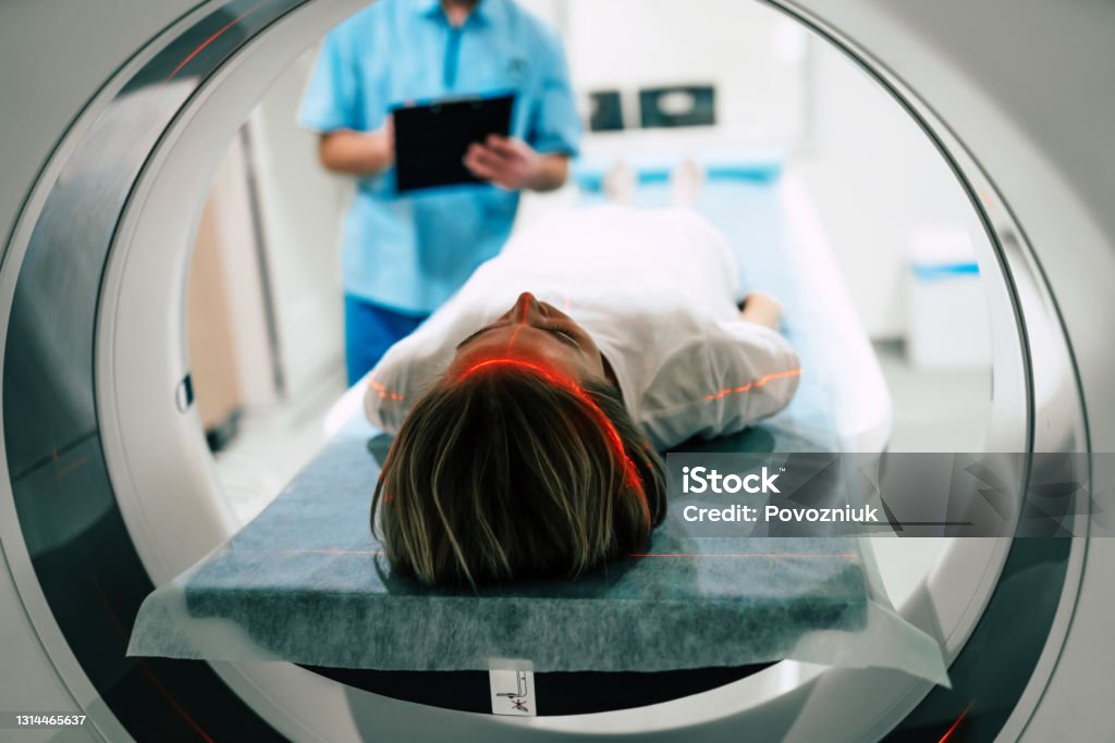 Young woman patient is ready to do magnetic resonance imaging in the modern hospital laboratory Radiologist Stock Photo