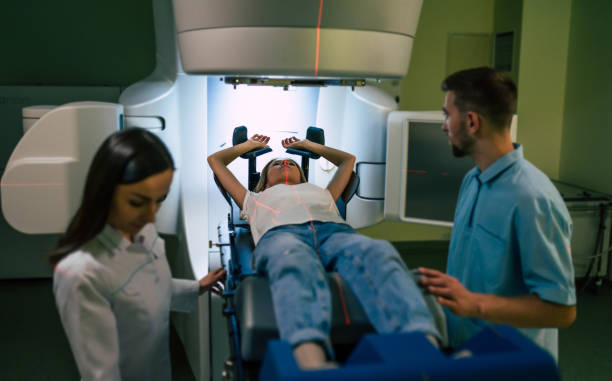 tratamiento oncológico en una clínica privada médica moderna u hospital con un acelerador lineal. equipo médico profesional trabajando mientras la mujer se somete a radioterapia para el cáncer - irradiation fotografías e imágenes de stock