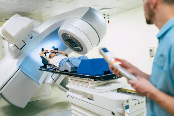 Photo of Cancer treatment in a modern medical private clinic or hospital with a linear accelerator. Professional doctors team working while the woman is undergoing radiation therapy for cancer