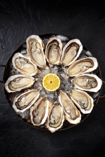 istock Oyster dozen, top shot on a black stone background 1314465794