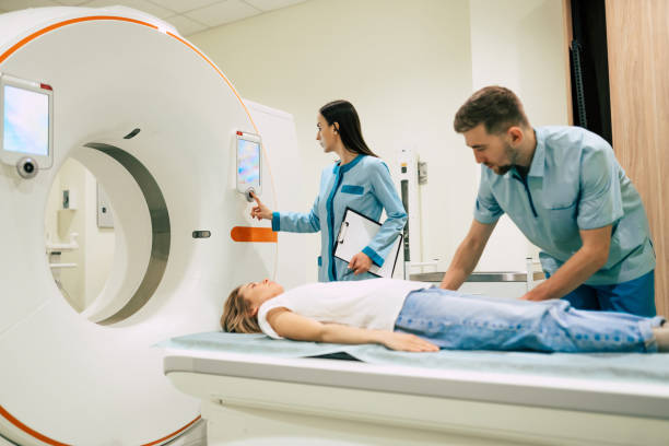 profesjonalny lekarz radiolog w laboratorium medycznym kontroluje obrazowanie metodą rezonansu magnetycznego lub tomografii komputerowej lub pet scan z pacjentką przechodzącą procedurę. - brain surgery mri scanner cat scan oncology zdjęcia i obrazy z banku zdjęć