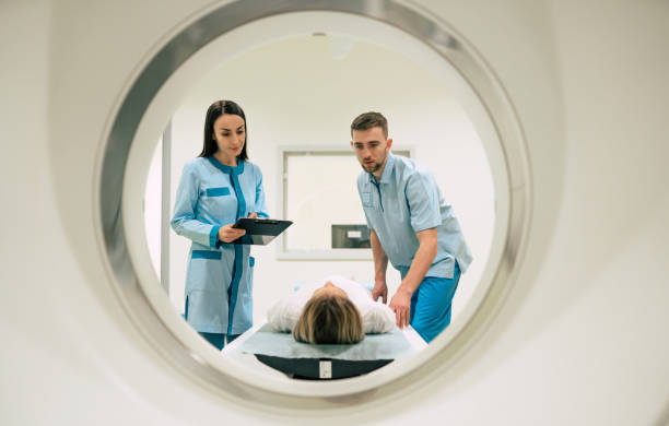 profesjonalny lekarz radiolog w laboratorium medycznym kontroluje obrazowanie metodą rezonansu magnetycznego lub tomografii komputerowej lub pet scan z pacjentką przechodzącą procedurę. - brain surgery mri scanner cat scan oncology zdjęcia i obrazy z banku zdjęć