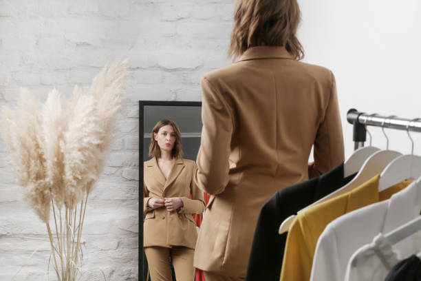 jeune femme choisissant des vêtements et essayant sur le blazer beige dans l’atelier de mode ou la garde-robe personnelle. - blazer photos et images de collection