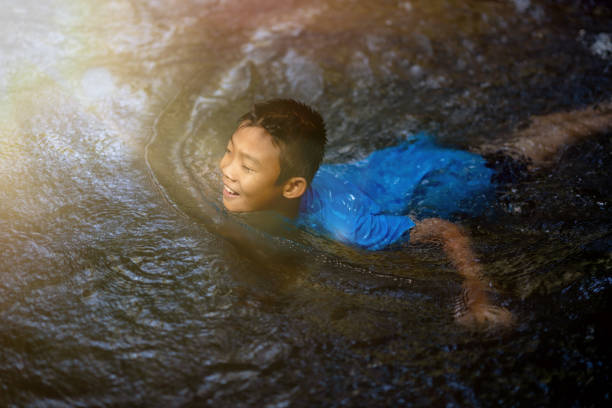 Kids playing and swimming in water fall on nature
