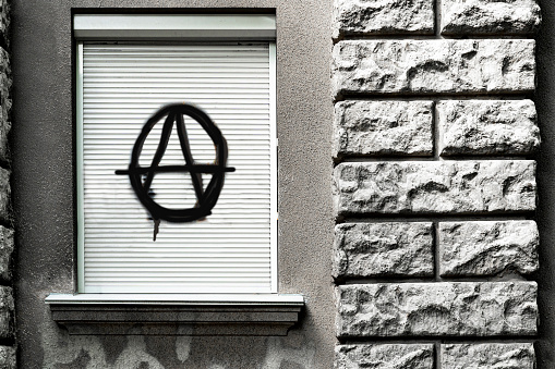black sign of anarchy on closed window. culture of anarchists, punks and street protests. Symbol of Anarchy painted on a window