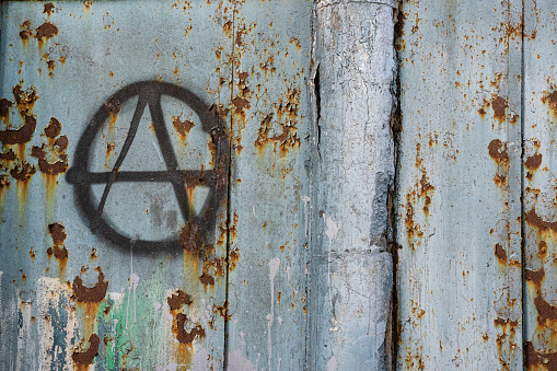 black sign of anarchy on an old fence. culture of anarchists, punks and street protests. Symbol of Anarchy painted on a wall