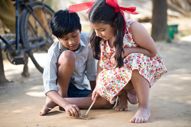 Children drawing with stick on sand Rural boy and girl drawing with stick on sand indian boy barefoot stock pictures, royalty-free photos & images