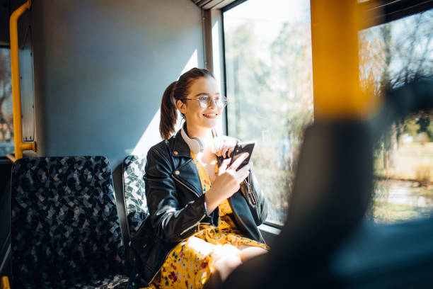 Young woman laughing while texting and listening to music on a bus Woman Listening Music On Phone and texting while Riding In Bus northern european stock pictures, royalty-free photos & images