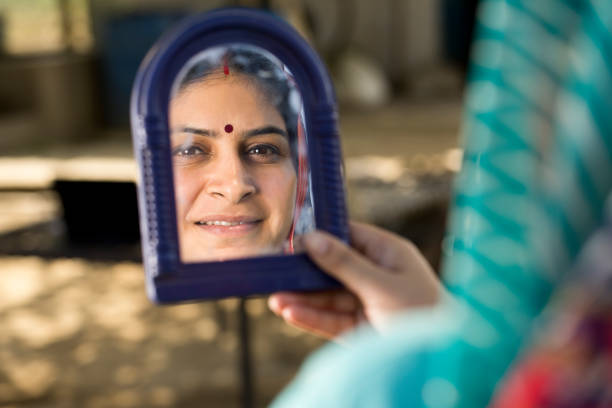 Rural Indian woman looking into her on mirror