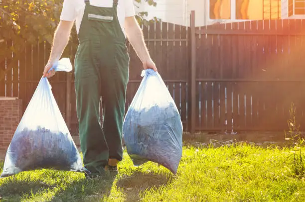 Photo of close-up of the gardener ,in the hands of bags of compost .sunlight on the right