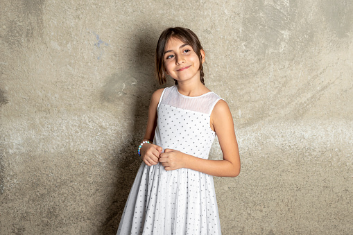 Little emotional teen girl in white shirt 11, 12 years old on an isolated white background. Children's studio portrait. Place text, to copy space for inscription, advertising children's goods.