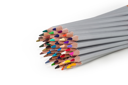 Bunch of colored wooden pencils painted gray on a white background, fragment close-up in selective focus
