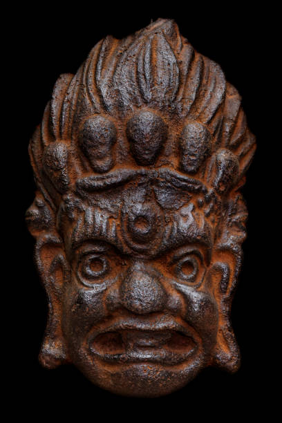 Traditional cast-iron mask of Mahakala, Great Time god, old and rusty, isolated on black background