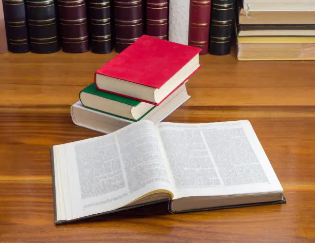 Photo of Open old book on wooden table against the other books