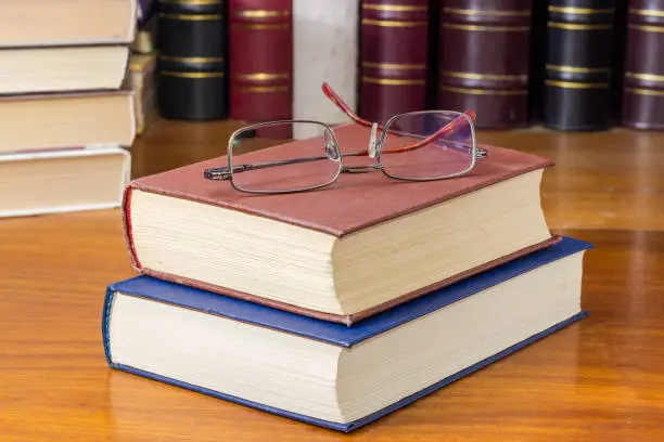 Photo of Eyeglasses on the two closed books against of other books