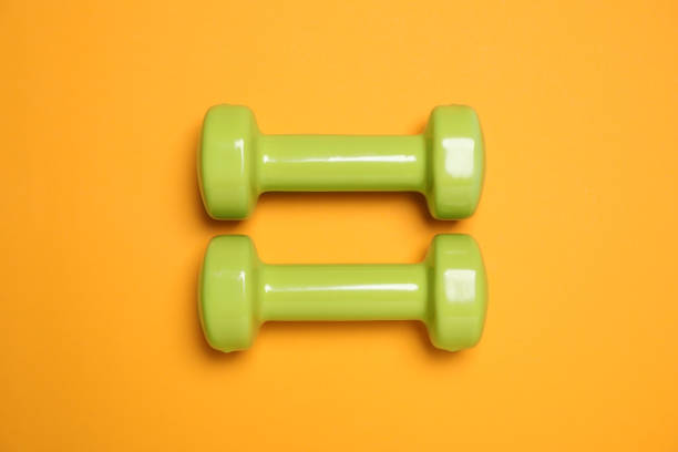 istock Dumbbells on orange background, flat lay. Sport equipment 1314480393