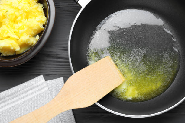 Frying pan and bowl with Ghee butter on dark wooden table, flat lay Frying pan and bowl with Ghee butter on dark wooden table, flat lay ghee stock pictures, royalty-free photos & images