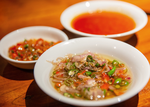 Close up shot of delicious spicy Balinese raw chili chopped with shallot and lemongrass ( sambal matah bali ). There's various chili condiment on the side.