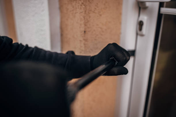 Criminal trying to brake in house One man, criminal dressed all in black with crowbar, trying to break through door in house. burglary crowbar stock pictures, royalty-free photos & images