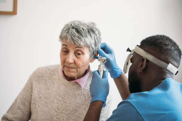 uma mulher mais velha tendo seus ouvidos verificados pelo médico ouvido - aparelho auditivo - fotografias e filmes do acervo