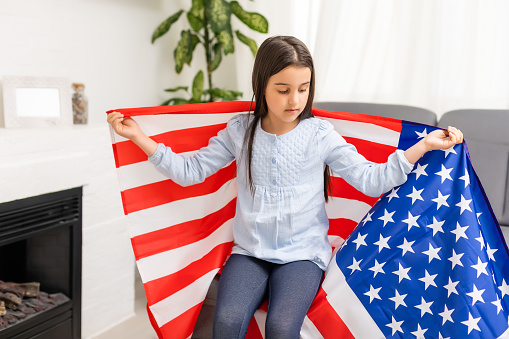 Cute little girl and USA flag on background.