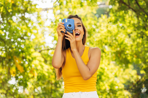 Happy beautiful woman with analog camera in the park