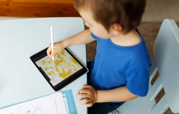 istock Cute boy in blue tshirt using digital tablet or computer for drawing his picture, using stylus . New technology art, online education 1314494182