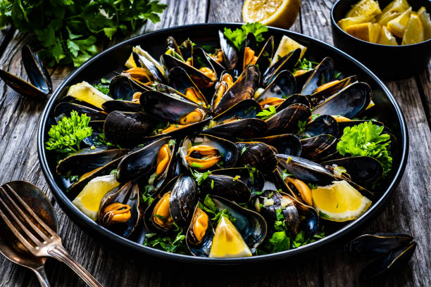 istock Cooked mussels with lemon and parsley on wooden table 1314501048