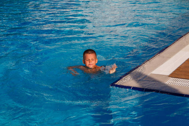 istock Seven-year-old tanned boy swims in pool squinting 1314503962