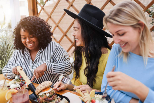 Young multiracial friends having breakfast outdoors in restaurant - Focus on asian girl face Young multiracial friends having breakfast outdoors in restaurant - Focus on asian girl face brunch stock pictures, royalty-free photos & images