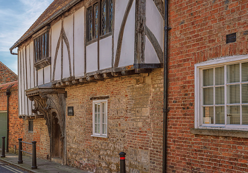 York, UK. April 23, 2021. An ancient half-timbered building with an ornate doorway. The upper floor is whitewashed and the lower half is of brick and stone.